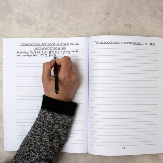 Someones arm as they write inside the nan tell me everything journal