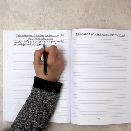 Someones arm as they write inside the nan tell me everything journal